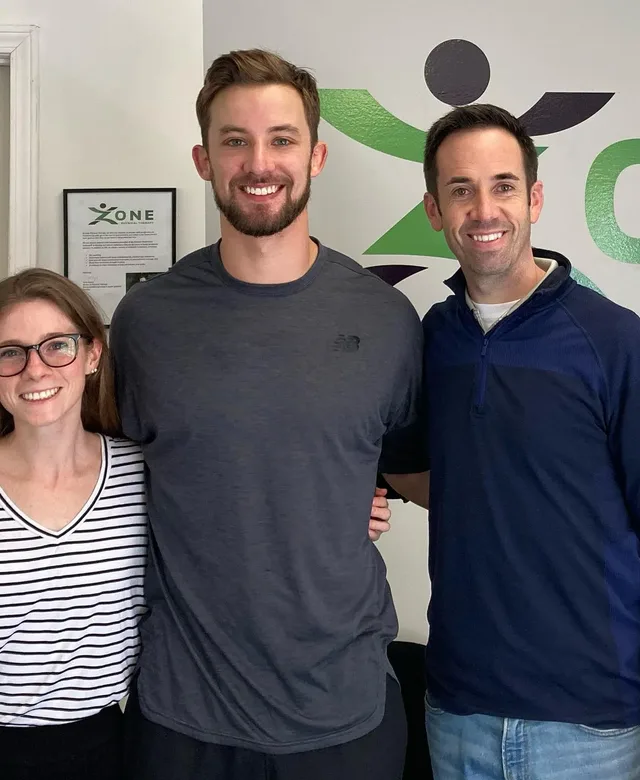 Zone Physical Therapy team members in front of the clinic's logo wall in Greer, SC